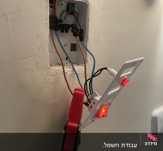 חוטי חשמל מחוברים לשקע בקיר עם כלי עבודה
